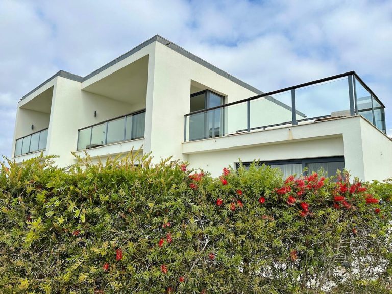 House with a balcony and a hedge