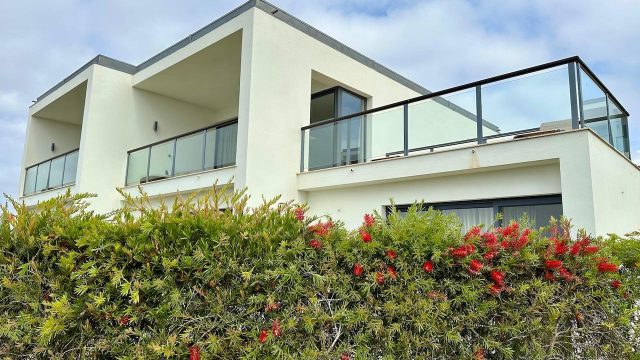 House with a balcony and a hedge